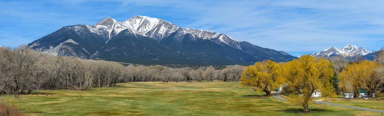 Spring Mountain valley - A panoramic view of a colorful mountain valley at base of snow-capped...