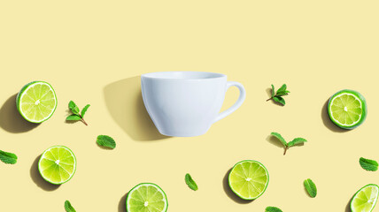 Obraz na płótnie Canvas Fresh limes with tea cup overhead view - flat lay