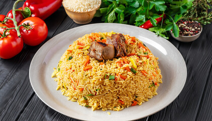 Uzbek pilaf and ingredients on black wooden background. Plov - rice prepared with vegetables and...