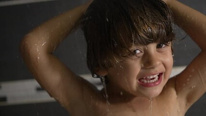 Child washing hair at shower bath in slow motion. Portrait face of a happy kid showering. Wash daily routine in slow motion bathing