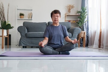 Fototapeta premium Tranquil Harmony: Senior Woman Discovers Inner Peace through Yoga and Meditation at Home