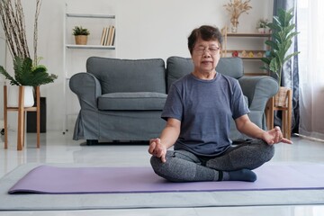 Fototapeta premium Tranquil Harmony: Senior Woman Discovers Inner Peace through Yoga and Meditation at Home