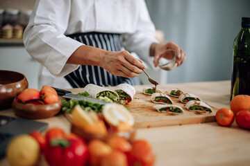 The skilled master chef prepares a vegetable wrap with great passion and care. Mix all the ingredients and materials carefully and precisely with expertise. Served with a flavorful sauce on top.