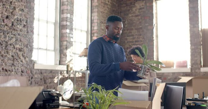 Diverse colleagues unpacking boxes with documents and office items in creative office in slow motion