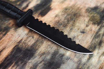Black knife. Hunting knife on a wooden background. Combat army knife made of high- quality stainless steel. Marine corps knife. - obrazy, fototapety, plakaty
