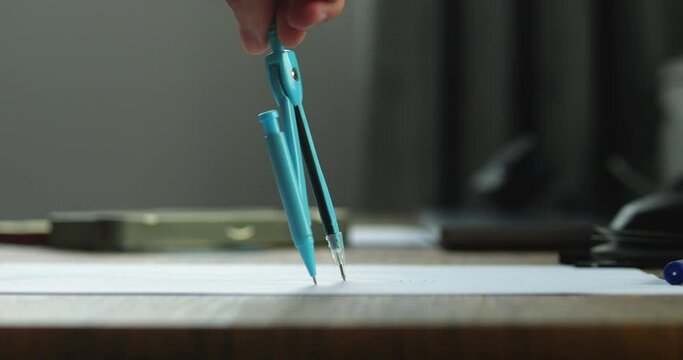 Close-up architecture designer draws circle with compass, professional engineer working, interior creator making project, drafting building. Close up person using compass with pencil to draw a drawing