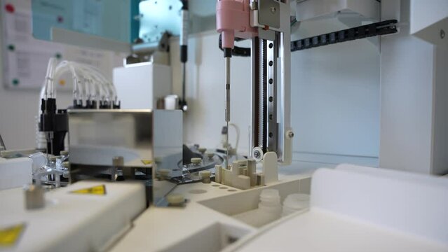 Close-up of a Long sharp laboratory needle moving fast on an modern analyzer moving and pipetting blood samples in a small medical clinic