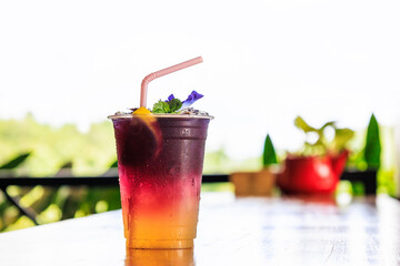 Butterfly pea or blue pea juice ice cool drink with lime on wooden table.