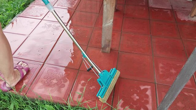 Cleaning the tile floor after the rain with a mop