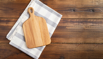 Cutting board over towel on wooden kitchen table. Top view