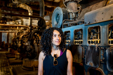 Portrait of a mixed race woman smiling while posing inside an abandoned factory.