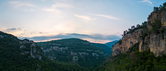 Panoramic view of steep limestone cliffs and tranquil valley at sunset