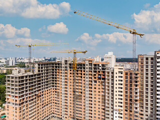 Fototapeta na wymiar city construction site with buildings and cranes against cloudy sky. aerial photo.