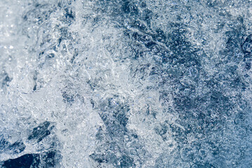 Fototapeta na wymiar Abstract blue sea water with white waves. Blue sea texture with waves and foam. Rough deep turquoise and blue Mediterranean sea. Sea water top view.