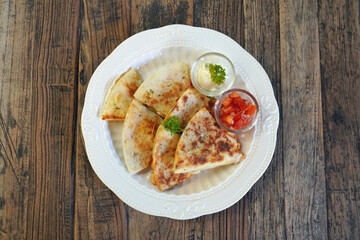 Quesadilla is a Mexican dish consisting of a tortilla that is filled primarily with cheese, and sometimes meats, spices, and other fillings, and then cooked on a griddle or stove. Top view