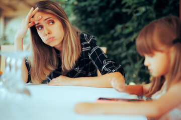 Tired Mother Sitting in a Restaurant Having a Headache. Unhappy stressed mom feeling overwhelmed...