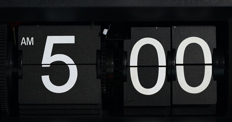 Flip clock displays the time as AM 5 o'clock white-lettered on a black background.