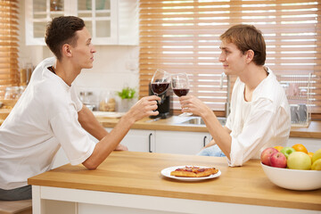 Fototapeta na wymiar LGBT gay couple talking with boyfriend and drinking wine in dining room