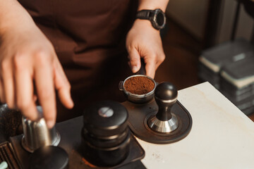 Closeup hand of barista preparation tampering coffee in portafilter for making espresso. Coffee making concept.
