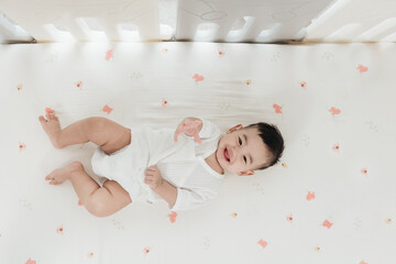 Adorable asian baby comfortable and good mood, Lying on a bed looking at camera. Baby healthcare...