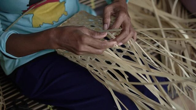 Details of the hands of bamboo craftsmen who make small bags manually from bamboo. Footage of the work of bamboo craftsmen who are producing bamboo bags manually