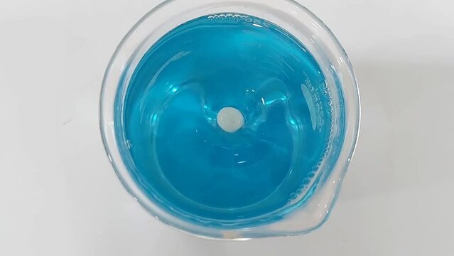 Top View. blue chemical liquid being stirred with a magnetic stirrer in a laboratory