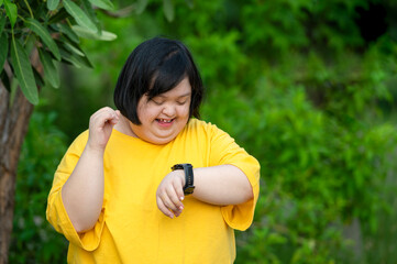 Girl with Down syndrome or autism looking at the time While walking outdoors in the park