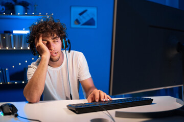 Arabic man gamer in a headset sleeps in a gaming chair at night near computer. Night training gaming. © Andrii Lysenko