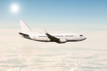 White passenger jet plane flies in the air above the clouds