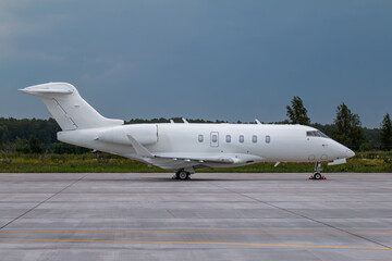 Modern white business jet on the airport apron on a cloudy day
