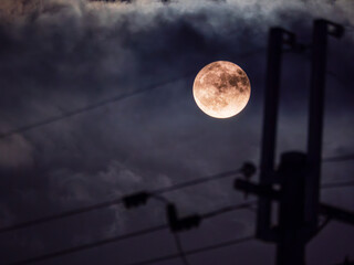 電信柱と雲から顔を出した満月
