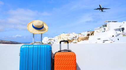 Summer concept with orange luggage with hat and landscape view of Oia town in Santorini island in...