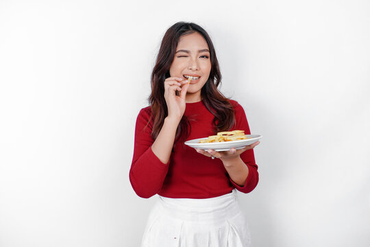 Image of smiling young Asian girl eating french fries isolated on white background