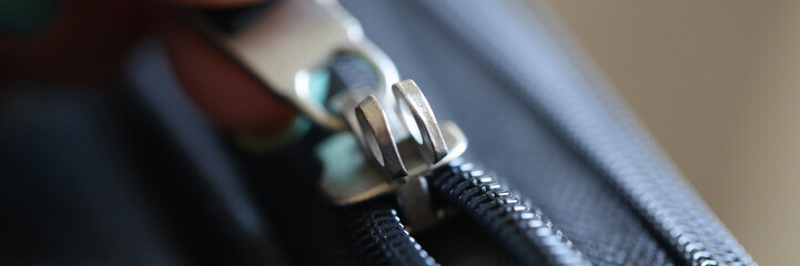 Female hand opening black brass zipper of suitcase