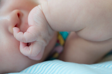 The picture captures a cute moment of a newborn baby attempting to explore by putting a finger in their nose, showcasing their curiosity and early motor skills development - 620412740