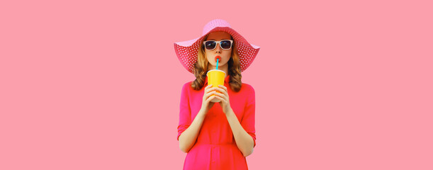 Summer portrait of beautiful young woman drinking fresh juice wearing straw hat, pink dress on...