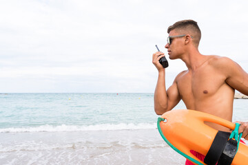 Handsome Lifeguard using the radio while working