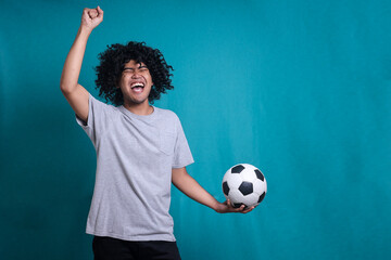 Happy curly man football fan screaming support favorite team hold soccer ball doing winner gesture. Sport victory, winning competition concept