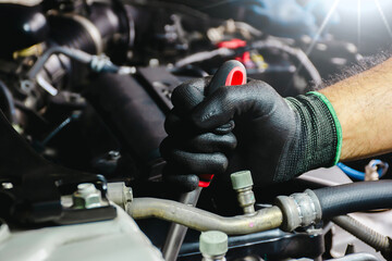 Auto mechanic hands in black gloves repairing a car engine. Car mechanic working on a car engine.