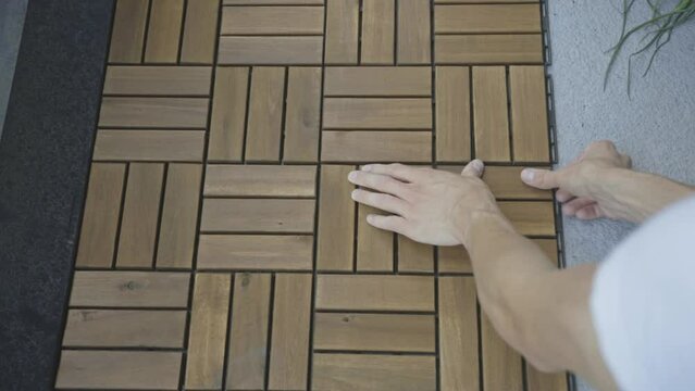 Unrecognizable Person Installing Wooden Decking Tiles At The Terrace. Close up