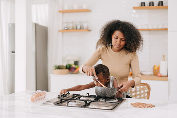 busy mom cooking food in kitchen stove island at home with playful naughtily kid boy lifestyle...