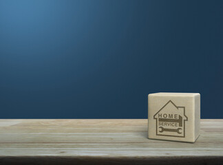 Hammer and wrench with house icon on wood block cube on wooden table over light blue wall, Business home service concept