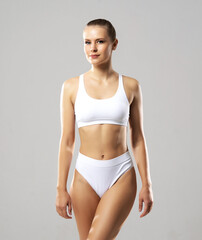 Fototapeta premium Young and beautiful slender girl in white swimsuit posing over white background. Healthcare, diet, sport and fitness concept.