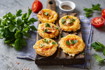 Hearty snack: mini pizzas with cheese, tomatoes and salami on a wooden board. close-up