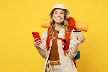Young woman carry backpack with stuff mat hold mobile cell phone credit card isolated on plain...