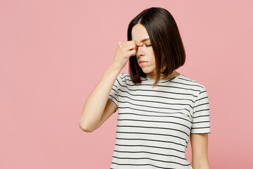 Young tired exhausted sad caucasian woman she wear casual clothes t-shirt keep eyes closed rubbing put hand on nose isolated on plain pastel light pink background studio portrait. Lifestyle concept