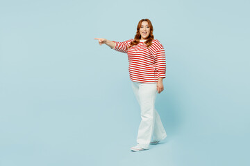 Full body side profile view cheerful young chubby overweight woman wear striped red shirt casual clothes point aside on area isolated on plain pastel blue background studio portrait Lifestyle concept