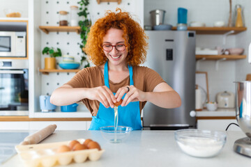 A vibrant red-haired woman bakes cookies in a modern kitchen, infusing warmth and joy. A delightful...