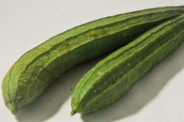 Two whole oyongs or gambas or luffa gourd isolated on a white background.