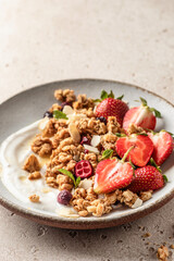 Healthy breakfast: fresh granola, muesli with yogurt, strawberry and honey close up on beige textured background. Text space